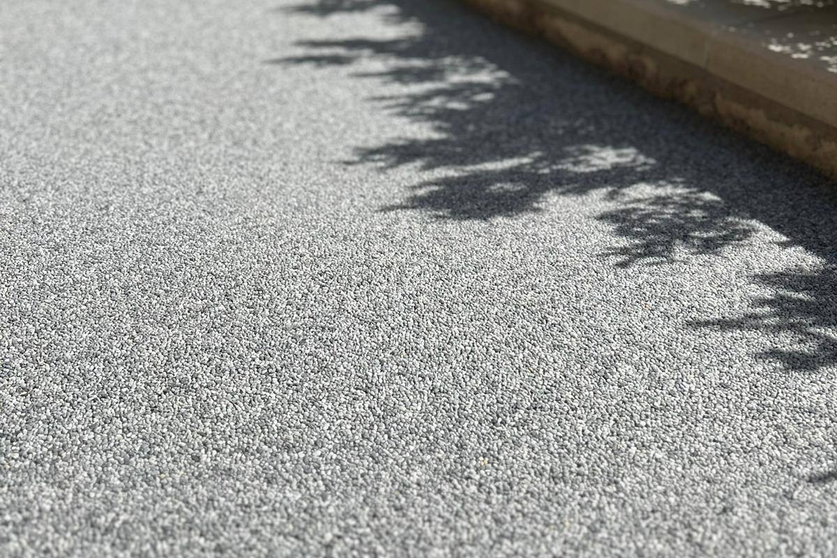 Resin bound walkway in a cool grey stone blend beside a limestone wall