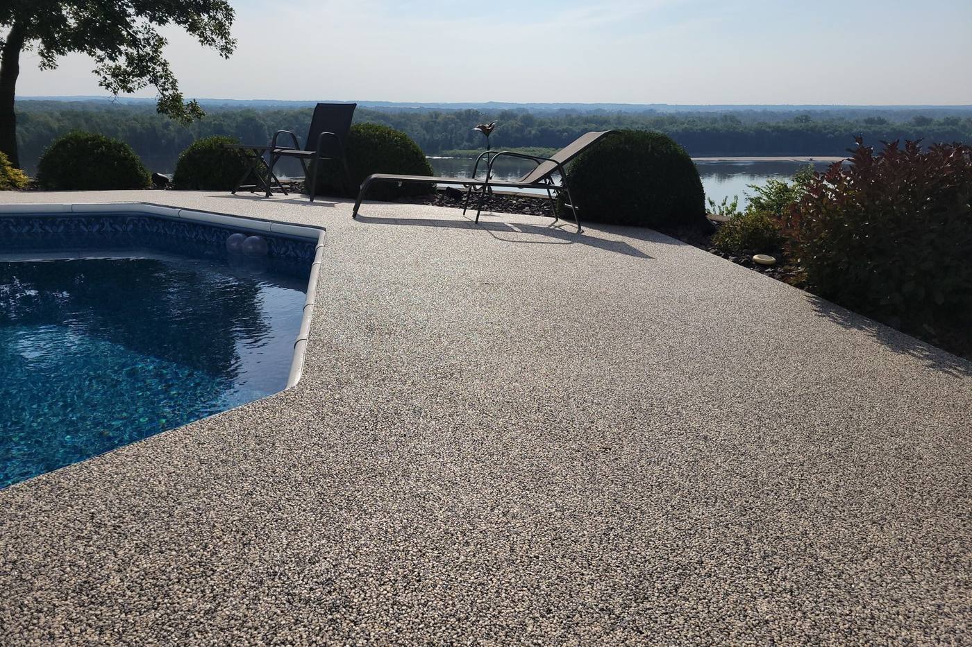 Resin bound pool deck in a light grey stone blend beside a swimming pool