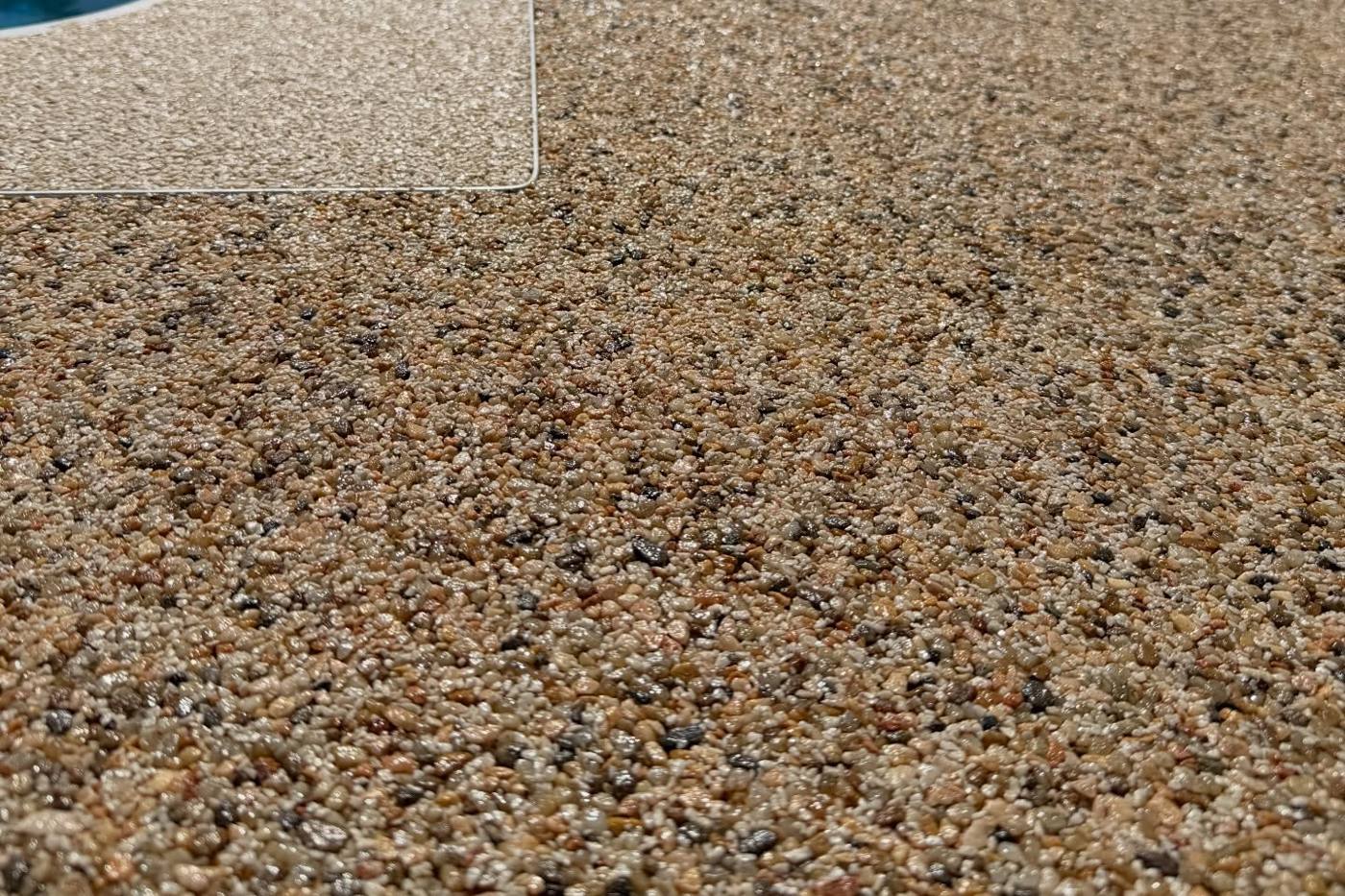 Close up of a resin bound pool surround in a mixed amber and grey stone blend