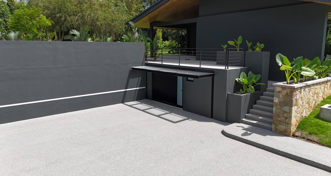 Resin bound patio in a soft grey blend outside a modern dark rendered house
