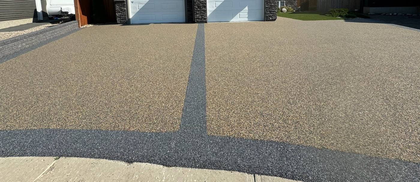Wide resin bound driveway in a tan stone blend with a charcoal contrast band